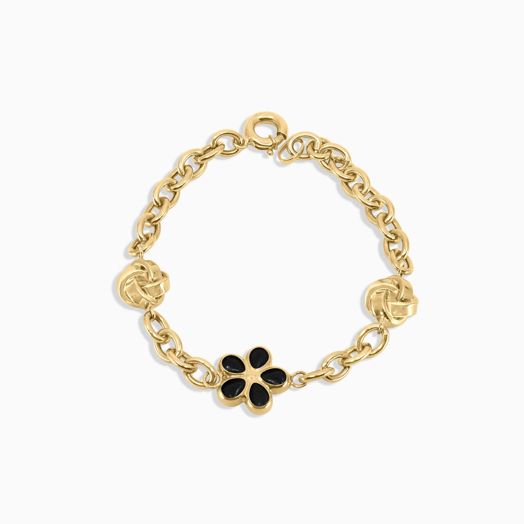 Gold bracelet with a black flower charm on a white background