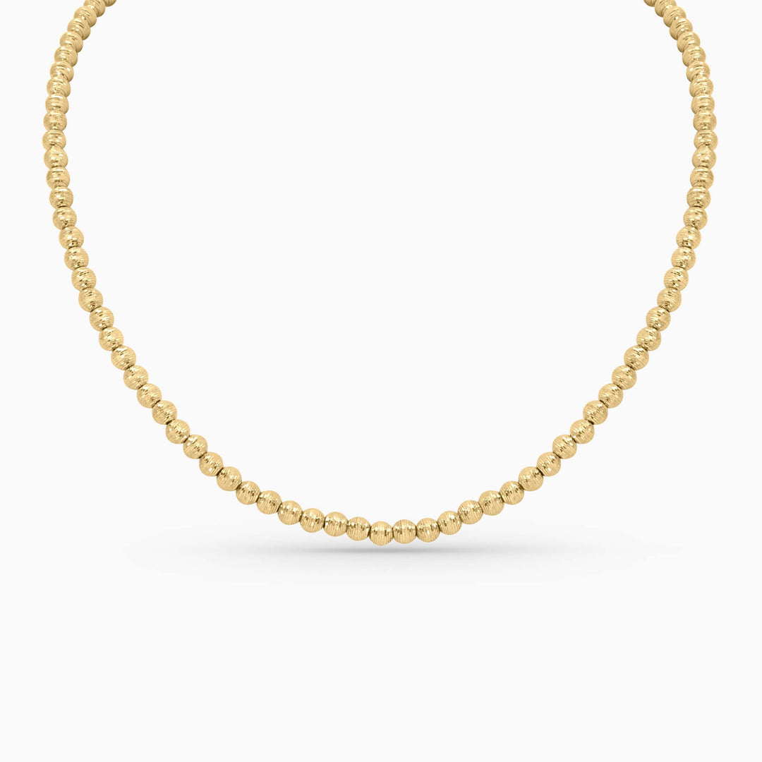 Gold beaded necklace on a white background