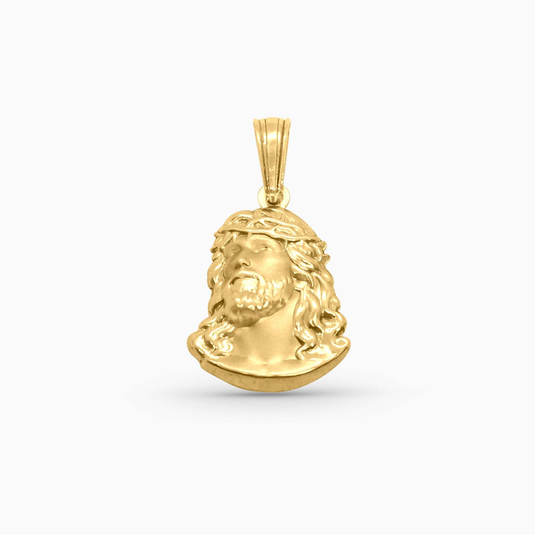 Gold pendant with a face design on a white background