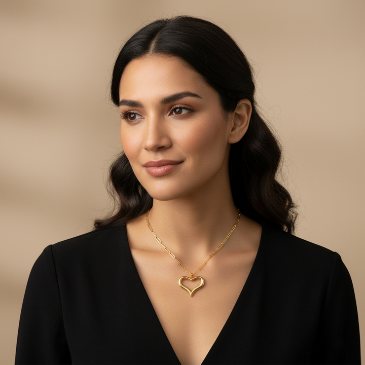 Woman wearing a gold heart-shaped necklace against a beige background