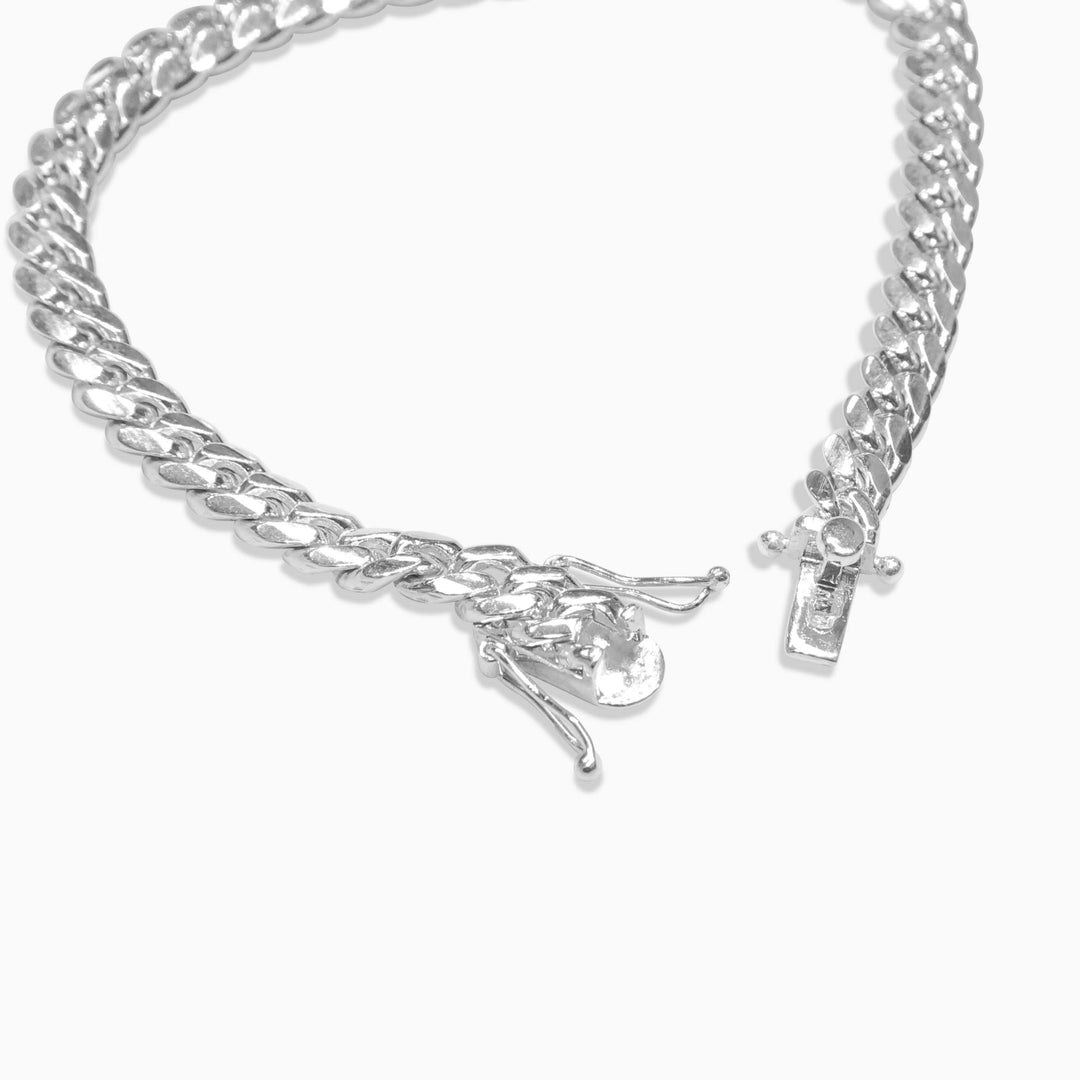 Silver chain bracelet with a small charm on a white background