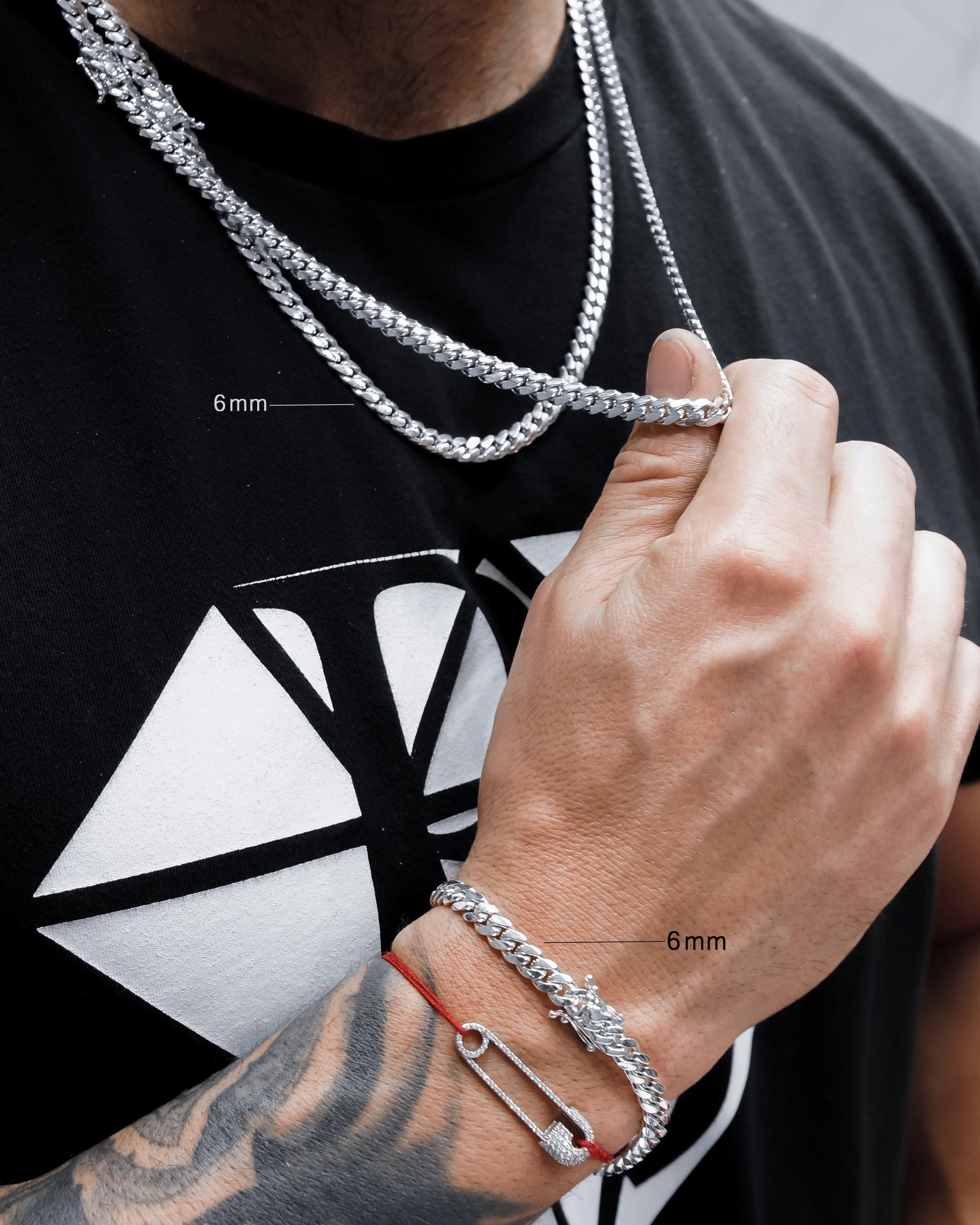 Person wearing a silver chain necklace and bracelet with close-up measurements on a black t-shirt with a white design.