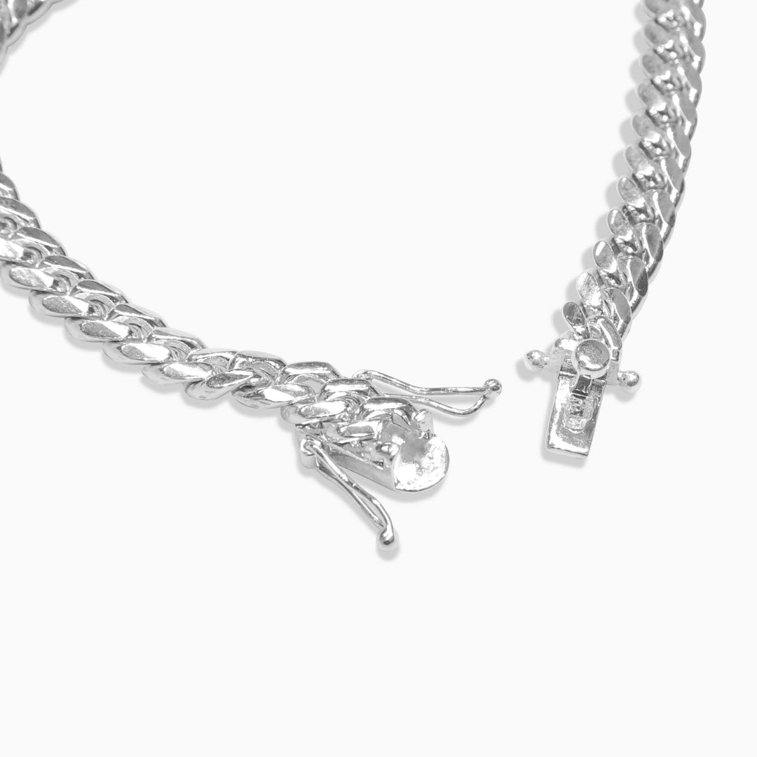 Silver chain bracelet with a small charm on a white background