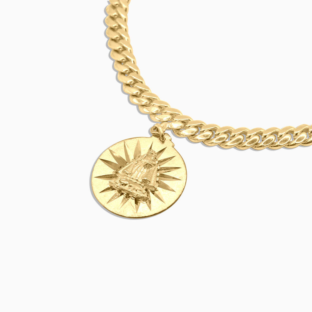 Gold chain necklace with a round pendant on a white background